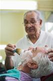 Senior man at work as barber shaving customer 