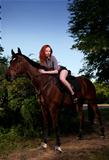 woman with red hair sitting on a horse