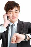 asian businessman checking time while talking on mobile phone