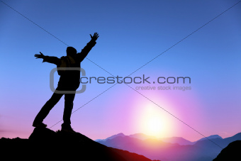 young man standing on the top of mountain and  watching the sunrise
