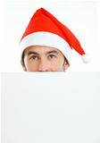 Male in Santa's hat hiding behind blank billboard