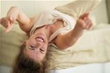 Laughing young woman laying on couch and pointing in camera