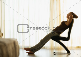 Young female relaxing on modern chair near window