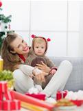 Smiling young mother spending Christmas with baby and pointing on copy space