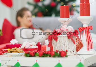 Closeup on table with Christmas decorations and female laying on couch in background