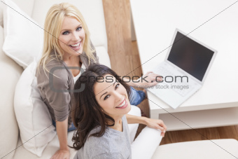 Two Young Women Using Laptop Computer At Home on Sofa