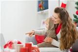 Happy young mother spending Christmas with baby and pointing on laptop