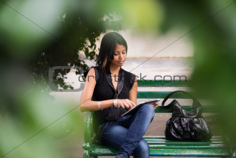 hispanic woman with digital tablet pc on bench