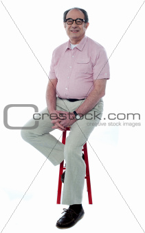 Confident senior man resting on stool