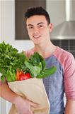 Good looking young man holding bag of fresh groceries