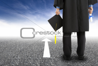 graduate standing on the road and forward arrow