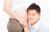 asian father listening to pregnant wife's tummy