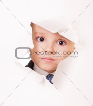 Serious kid looks through a hole in paper