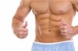Closeup on man with abdominal muscles showing thumbs up