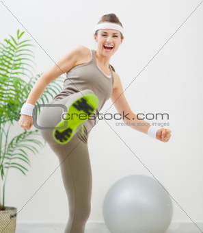 Happy fitness woman kicking in camera