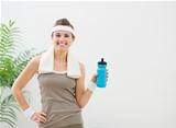Portrait of happy woman in sportswear with towel and bottle of water