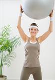 Smiling healthy woman making exercise with fitness ball