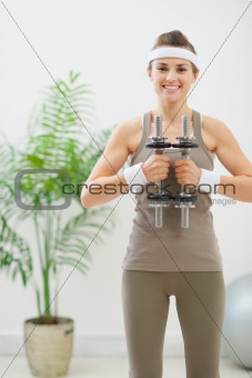 Happy woman in sportswear holding dumbbells