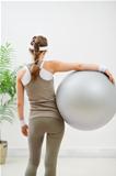 Fitness young woman with fitness ball. Rear view
