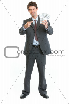 Smiling businessman pointing on packs of dollars