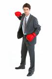 Businessman in boxing gloves swinging arm to strike