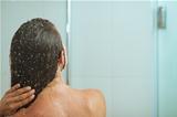 Woman bathing in shower under water jet. Rear view