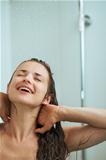 Happy woman bathing in shower under water jet