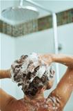 Woman applying shampoo in shower. Rear view