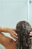 Woman washing hair in shower under water jet. Rear view