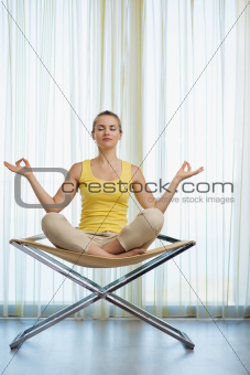 Young woman meditating on modern chair