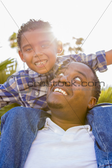 Happy Mixed Race Father and Son Playing Piggyback in the Park.
