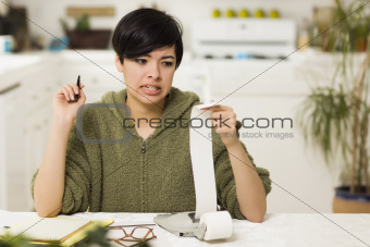 Mixed Race Young Female Agonizing Over Financial Calculations in Her Kitchen.