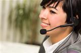 Attractive Young Mixed Race Woman Smiles Wearing Headset in Office Setting.
