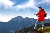 young man touching the  tablet pc on the top of mountain