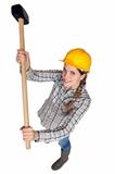 A female construction worker holding a sledgehammer.