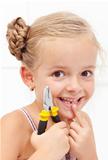 Little girl smiling holding her missing tooth with pliers