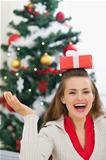 Happy young woman balancing Christmas present box on head