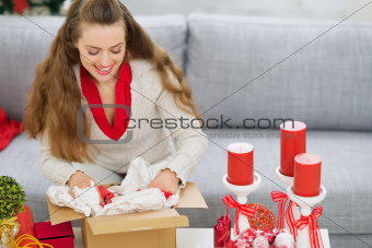 Happy young woman packing parcel with Christmas gift