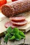 sliced meat sausage salami on wooden board with  green herbs