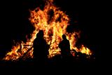 Three persons in front of bonfire