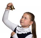 Young school girl looking to golden bell on white background 