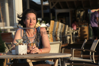 Woman sitting in outdoor cafe with glas of white vine