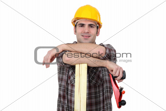 Carpenter posing with plank of wood and plane
