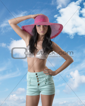 sexy brunette with shorts, hat and hand on the hip