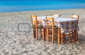 Greek taverna table and chairs on sandy beach