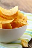 potato chips in a white bowl on a wooden table