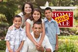 Happy Hispanic Family in Front of Sold Home for Sale Real Estate Sign.