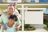 African American Family In Front of Blank Real Estate Sign and New House.