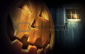 Glowing pumpkin at night in front of barn door