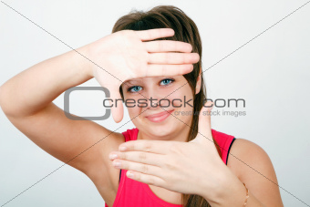 girl looks through a framework of hands 